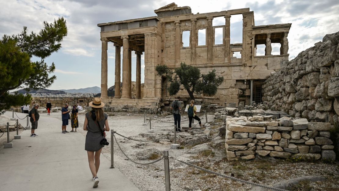 Tourists walk toward the Erechtheion on the Acropolis hill in Athens on June 4. 