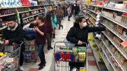 CHELSEA, MA - MARCH 13: A woman in a protective mask shops as a line of shoppers stretch to the back of the store waiting to check-out at the Market Basket in Chelsea, MA on March 13, 2020. People stock up amid coronavirus concerns. (Photo by Bill Greene/The Boston Globe via Getty Images)