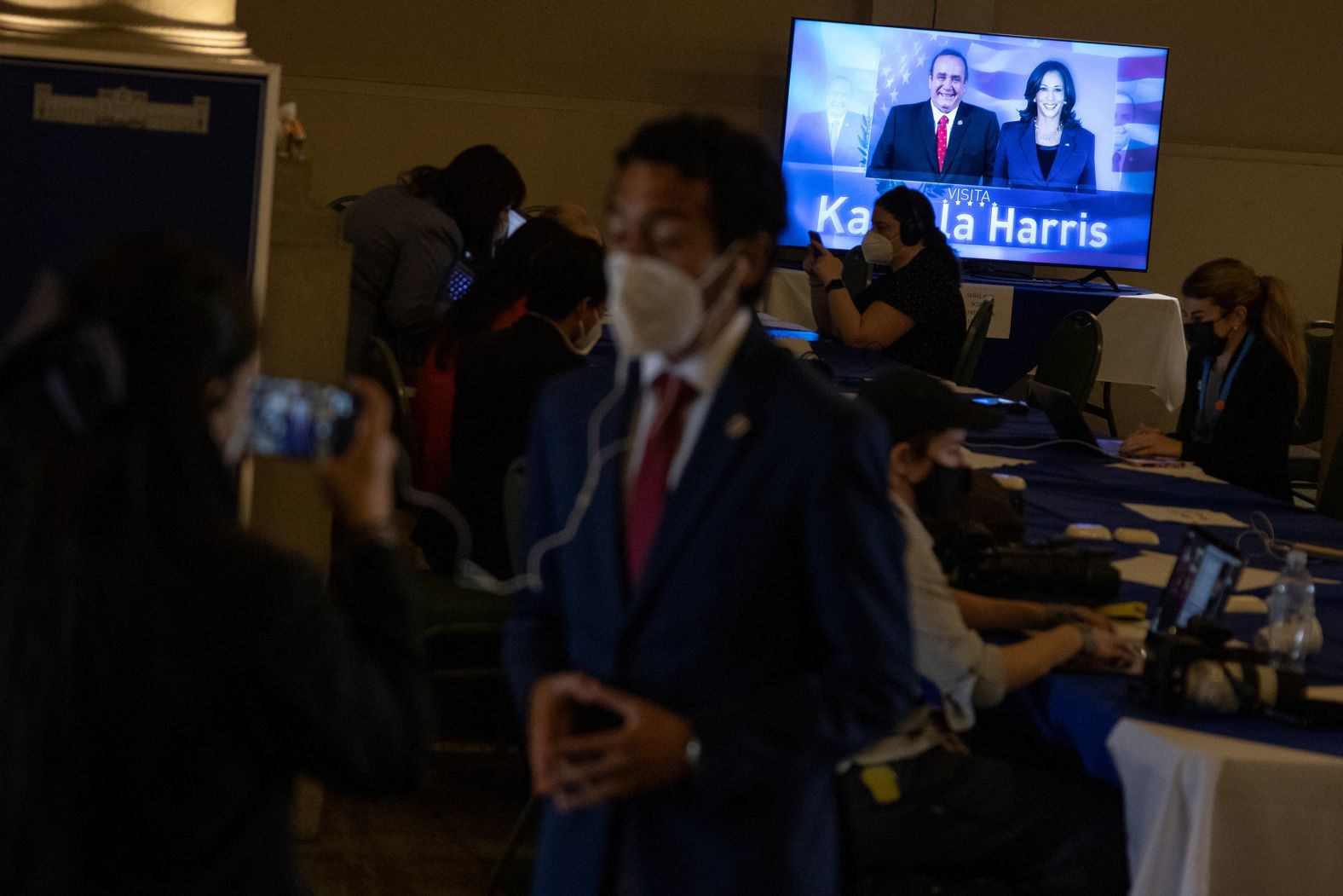 Media members work as a screen shows an image of Guatemala's President Alejandro Giammattei and Harris in Guatemala City on June 7.