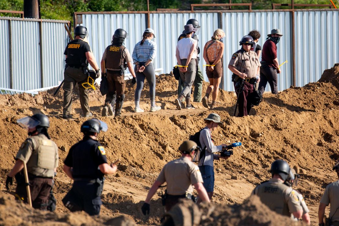 Activists are walked through an Enbridge Line 3 pump station Monday after being arrested.