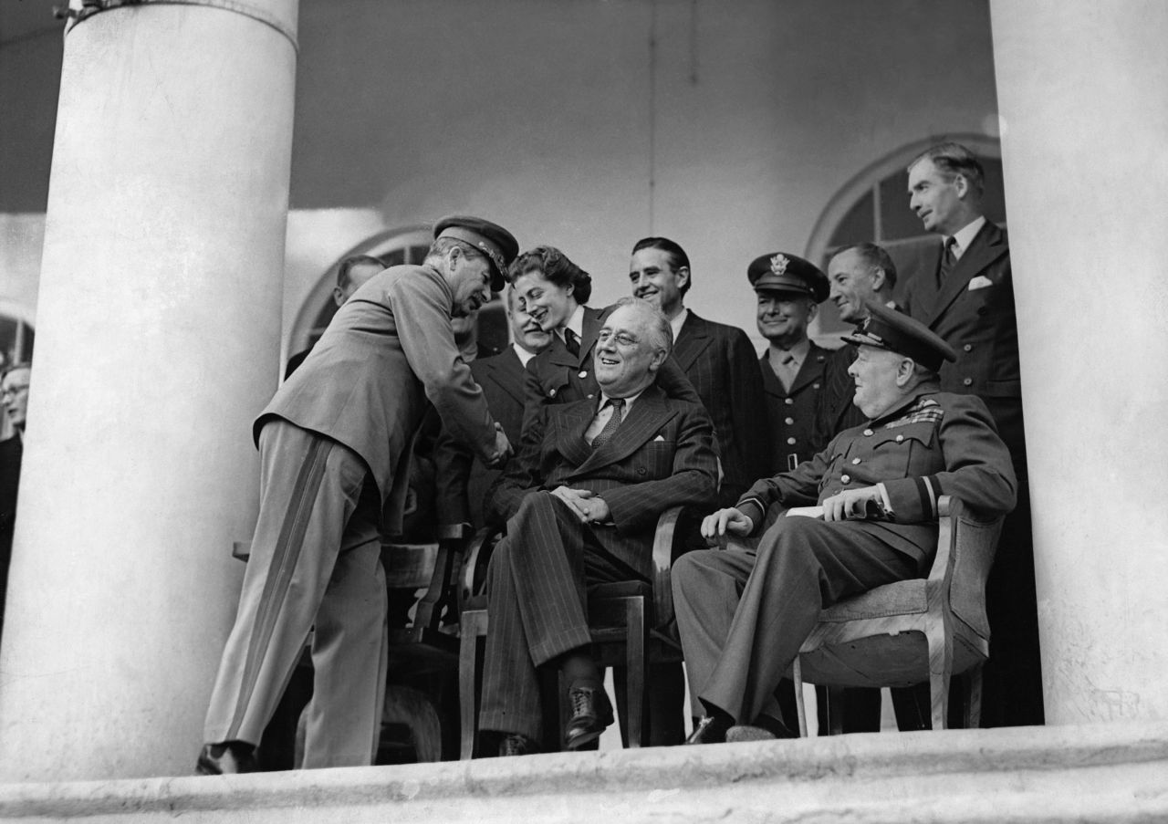 Soviet leader Joseph Stalin shakes hands with Sarah Churchill, daughter of British Prime Minister Winston Churchill, next to US President Franklin D. Roosevelt in 1943. Stalin, Roosevelt and Churchill, right, were meeting at the Soviet embassy in Tehran, Iran, to discuss strategy during World War II. They were allies against the Axis Powers.