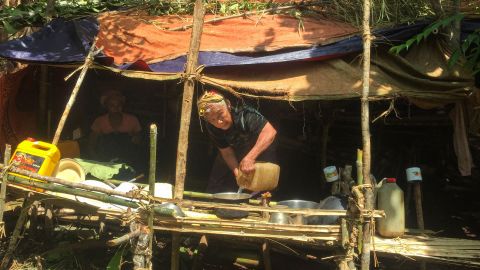 This picture taken on June 1, 2021 shows a woman pouring water in a makeshift hut in a jungle area in Demoso, Kayah state, after people fled from conflict zones where fighting between the Myanmar military and members of the People's Defence Force (PDF) took place.