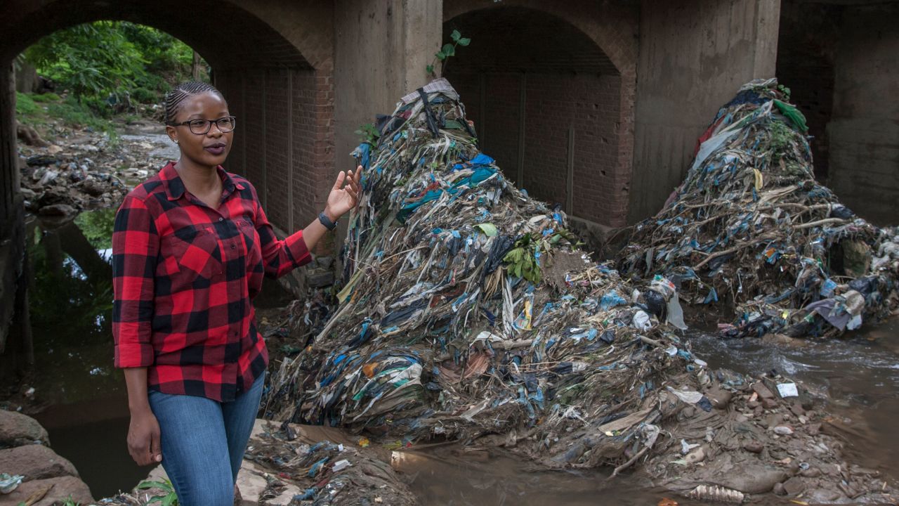 Gloria Majiga-Kamoto stands speaking in front of the Mudi River bridge where lots of banned thin plastic bags and other waste are trapped in Malawi's commercial city of Blantyre, February 21, 2021.