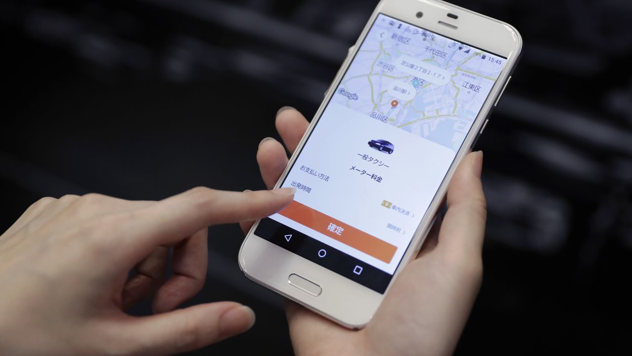 An attendant demonstrates the Didi Chuxing taxi-hailing application on a smartphone for a photograph at the SoftBank World 2018 event in Tokyo, Japan, on Thursday, July 19, 2018. SoftBank Group Corp. and China's Didi Chuxing unveiled a taxi-hailing platform for Japan, becoming the latest venture to bet on a market that has lagged behind the rest of the world. Photographer: Kiyoshi Ota/Bloomberg via Getty Images