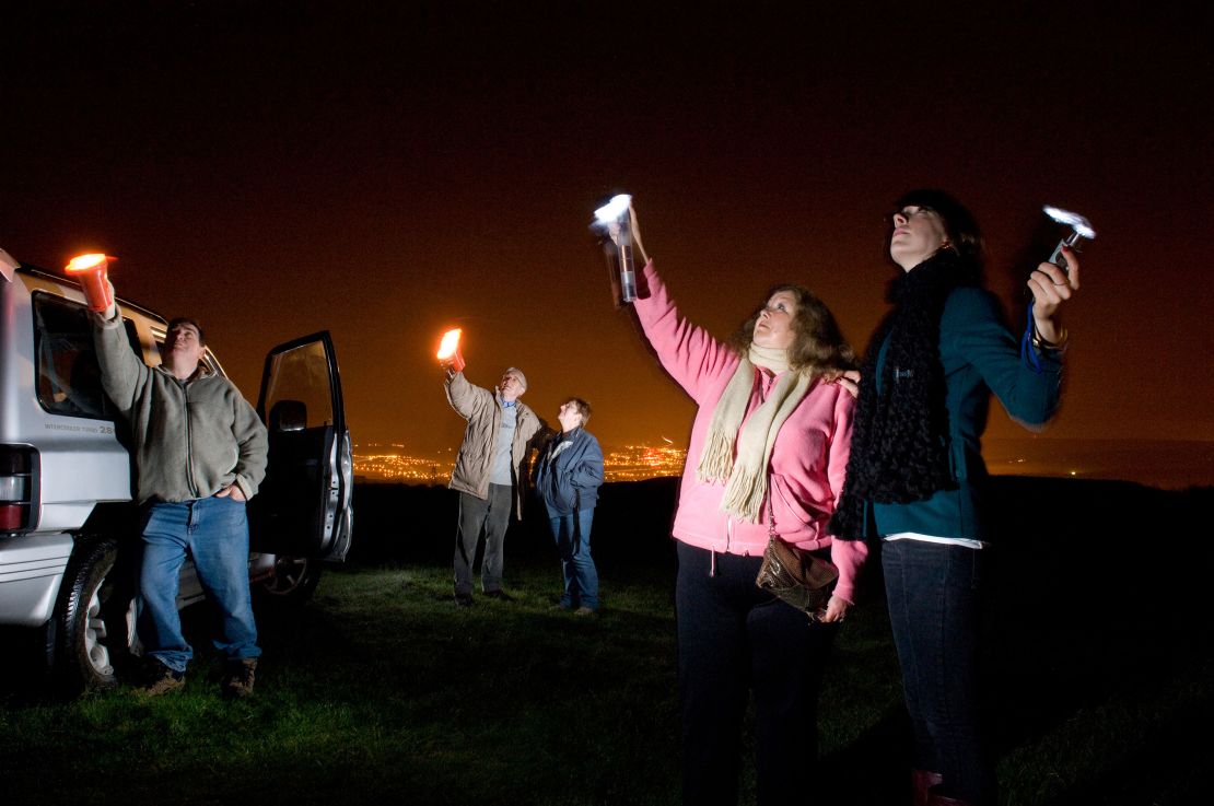 UFO spotters use flashlights to look for stars and aliens in the night sky in South Wales, Australia, in 2008. 