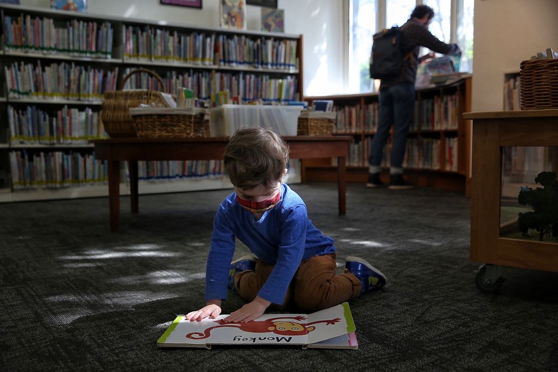 Libraries are slowly re-opening. Two-year-old Frank visited the Oakland Public Library's Rockridge Branch with his father.
