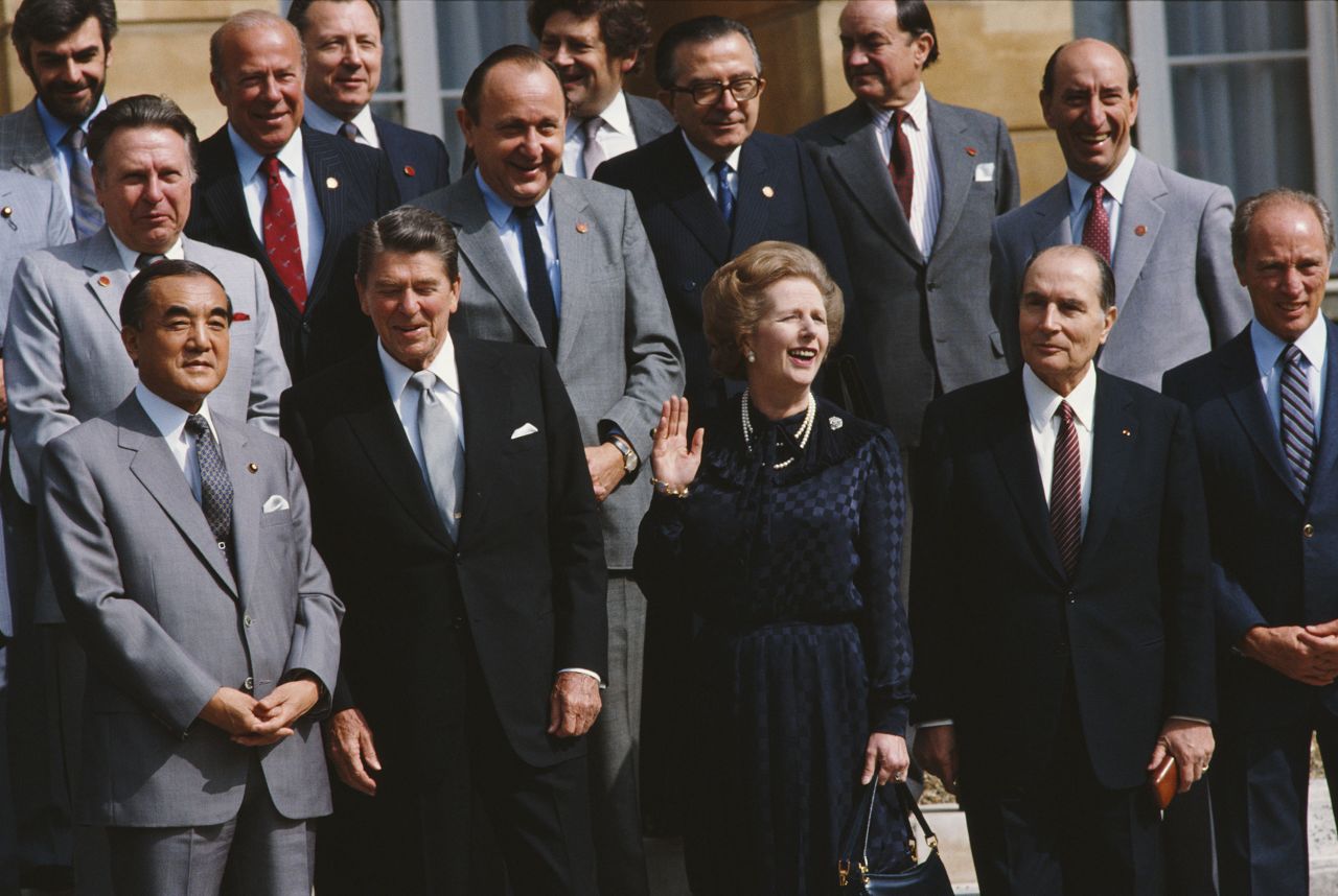 British Prime Minister Thatcher waves and takes questions from the media during a photocall with other world leaders at the steps of the Lancaster House in London during the 10th G7 summit in 1984. Standing near her are Japanese Prime Minister Yasuhiro Nakasone, US President Ronald Reagan, French President Francois Mitterrand, and Canadian Prime Minister Trudeau.