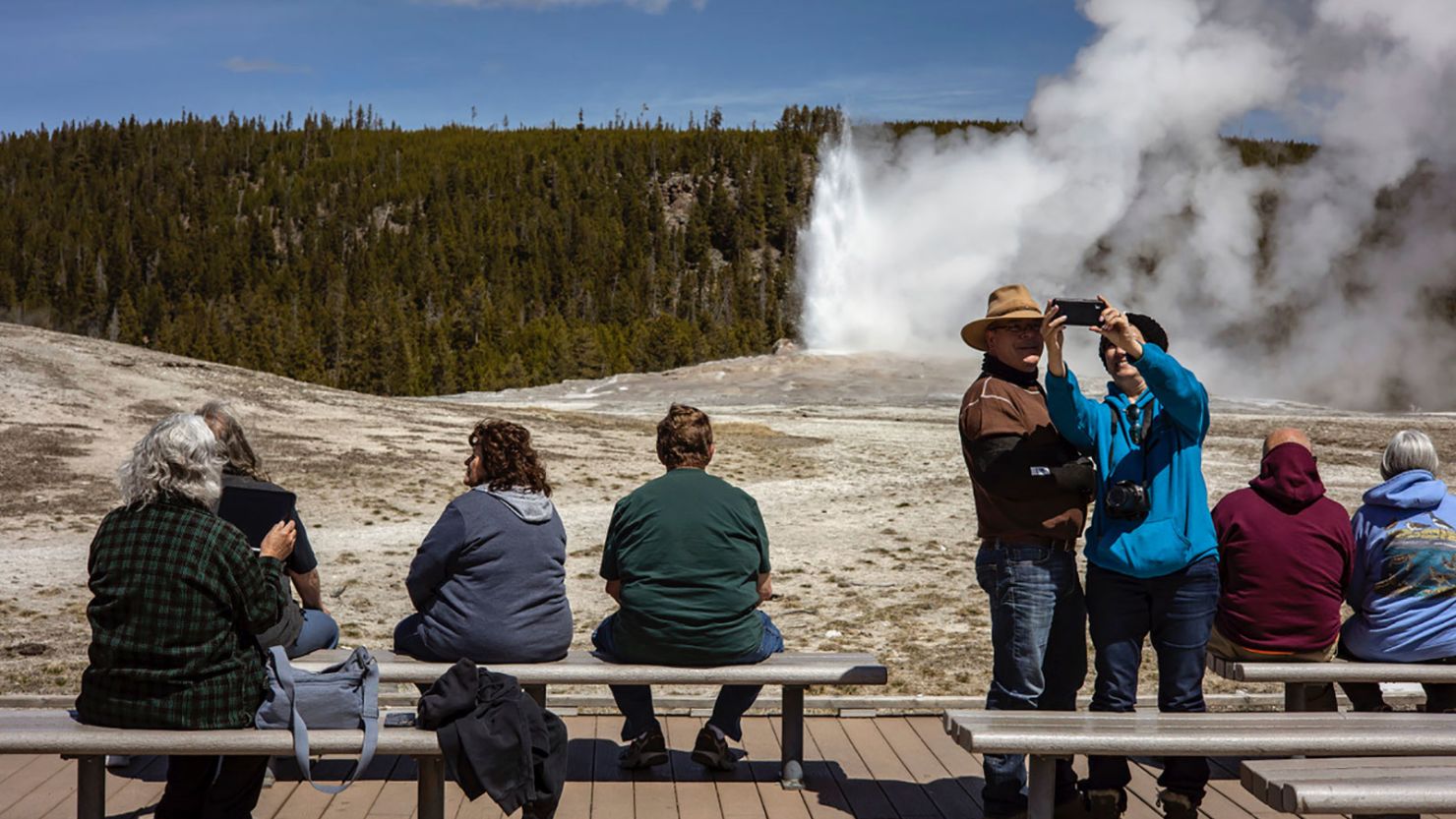 Tourists watch Old Faithful erupt in Yellowstone National Park on April 29, 2021, in Wyoming 