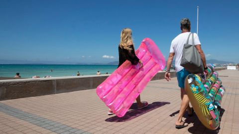 Tourists walk holding inflatable mattress at Palma Beach in Palma de Mallorca on June 7, 2021. - Spain opened its borders to vaccinated travellers from all over the world, hoping an influx of visitors will revitalise an all-important tourism sector that has been battered by the coronavirus pandemic. (Photo by JAIME REINA / AFP) (Photo by JAIME REINA/AFP via Getty Images)