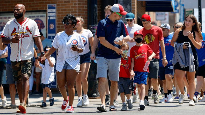 People cross a street as they make their way towards Chicago's Wrigley Field during baseball game, Friday, June 11, 2021, as Chicago and rest of Illinois fully reopens ending an over a year-long COVID-19 restrictions. (AP Photo/Shafkat Anowar)