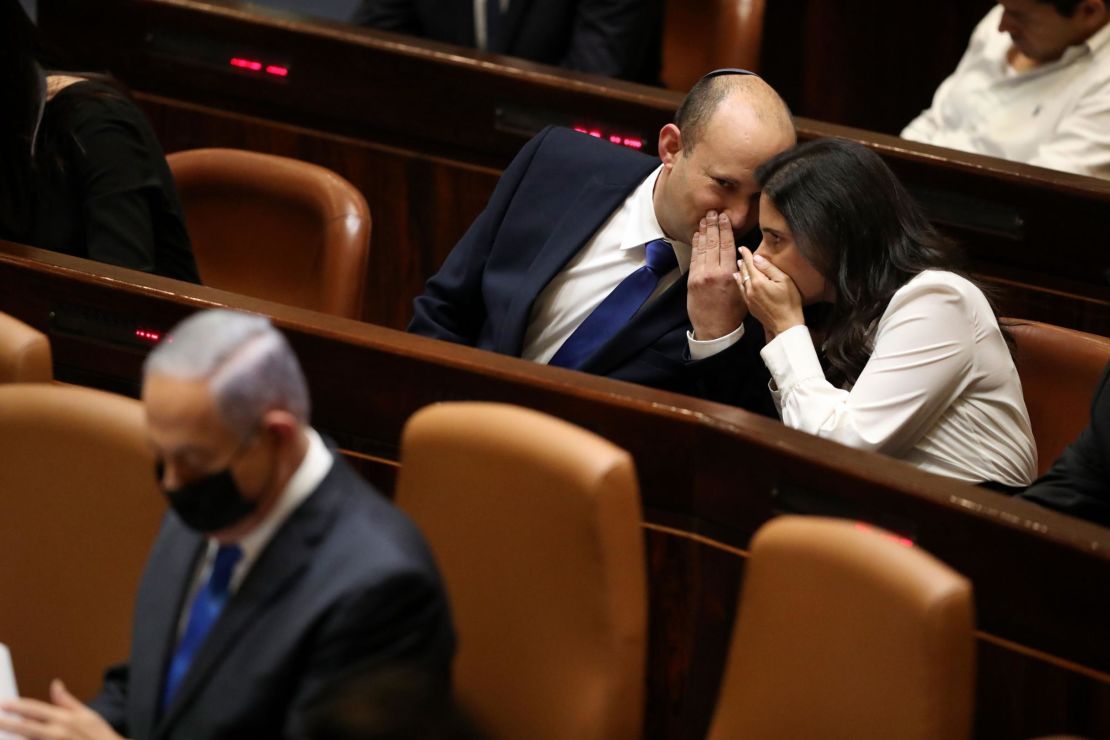 Israel's new Prime Minister Naftali Bennett and his coalition partner Ayeet Shaked speak behind Benjamin Netanyahu during the Knesset session.