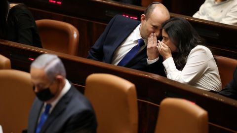 Israel's new Prime Minister Naftali Bennett and his coalition partner Ayeet Shaked speak behind Benjamin Netanyahu during the Knesset session.