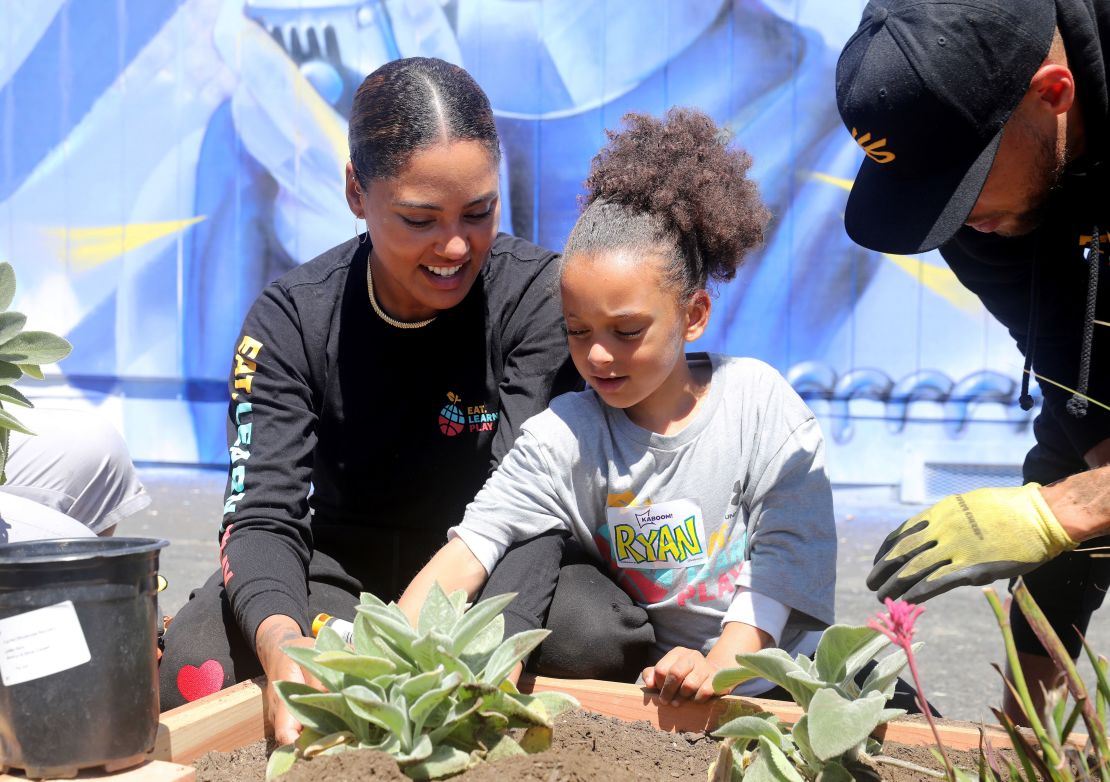 Ayesha Curry and daughter Ryan add plants to the garden area.