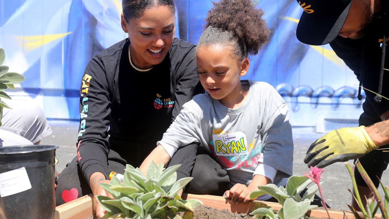 Ayesha Curry and daughter Ryan add plants to the garden area.