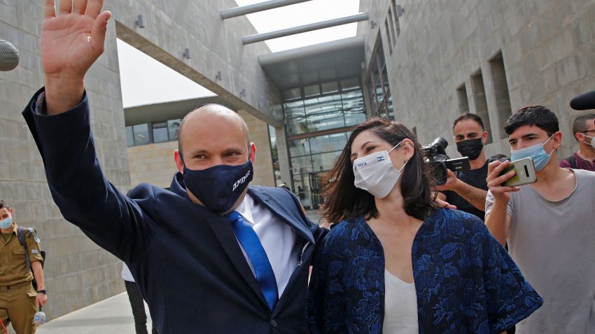 Israel's Naftali Bennett, leader of the right wing 'New Right' Yamina party, waves as he walks with his wife Gilat at a polling station where they voted on March 23, 2021 in the city of Raanana in the fourth national election in two years. - The former defence minister and religious nationalist has campaigned against Prime Minister Benjamin Netanyahu and not ruled out joining a coalition to oust him. (Photo by GIL COHEN-MAGEN / AFP) (Photo by GIL COHEN-MAGEN/AFP via Getty Images)