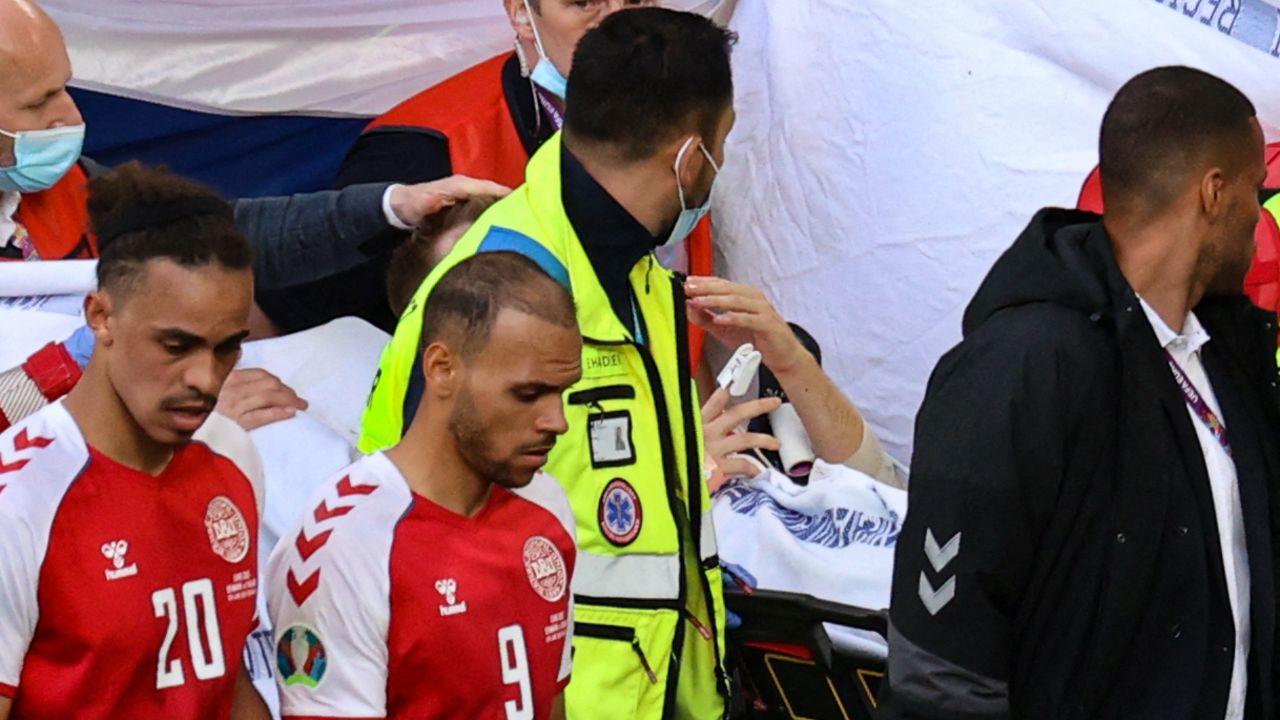 Martin Braithwaite walks alongside Christian Eriksen as he is taken from the field.