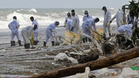 Members of the Sri Lanka Navy remove debris washed ashore from the burning container ship, in the sea off Colombo harbor on May 31.