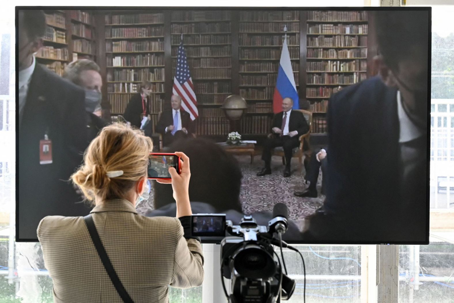 A journalist takes a picture of a screen displayed in the press room.