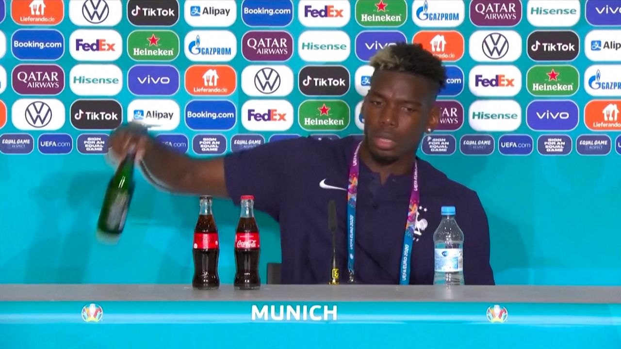 Pogba, who starred in France's 1-0 victory against Germany, removes a Heineken bottle during a press conference.