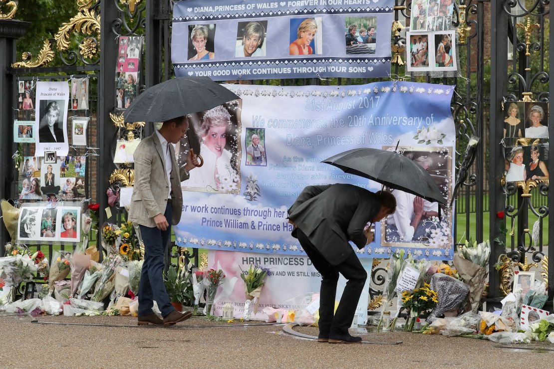 The brothers look upon flowers, photos and other souvenirs left as a tribute to Princess Diana near the Sunken Garden at Kensington Palace in London on August 30, 2017.