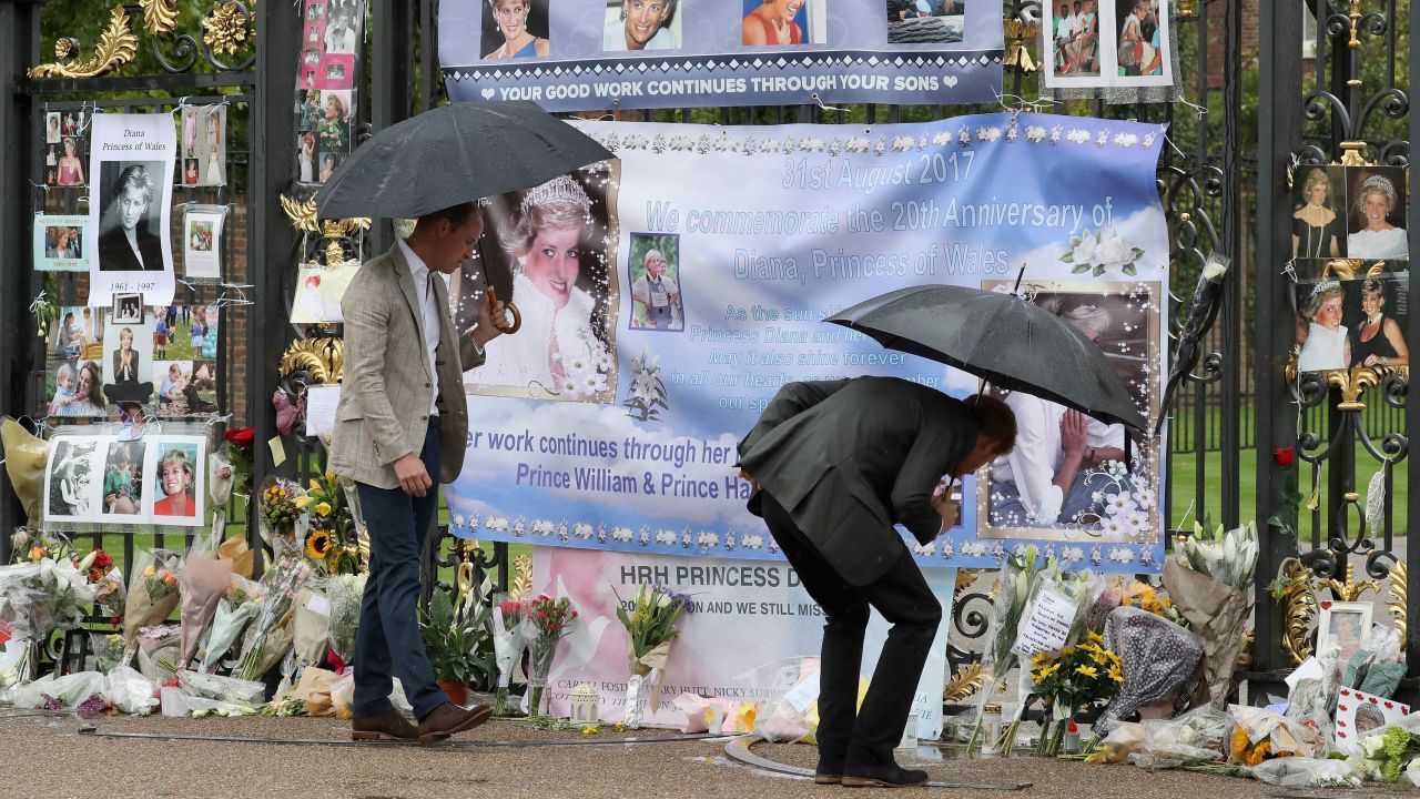 The brothers look upon flowers, photos and other souvenirs left as a tribute to Princess Diana near the Sunken Garden at Kensington Palace in London on August 30, 2017. 