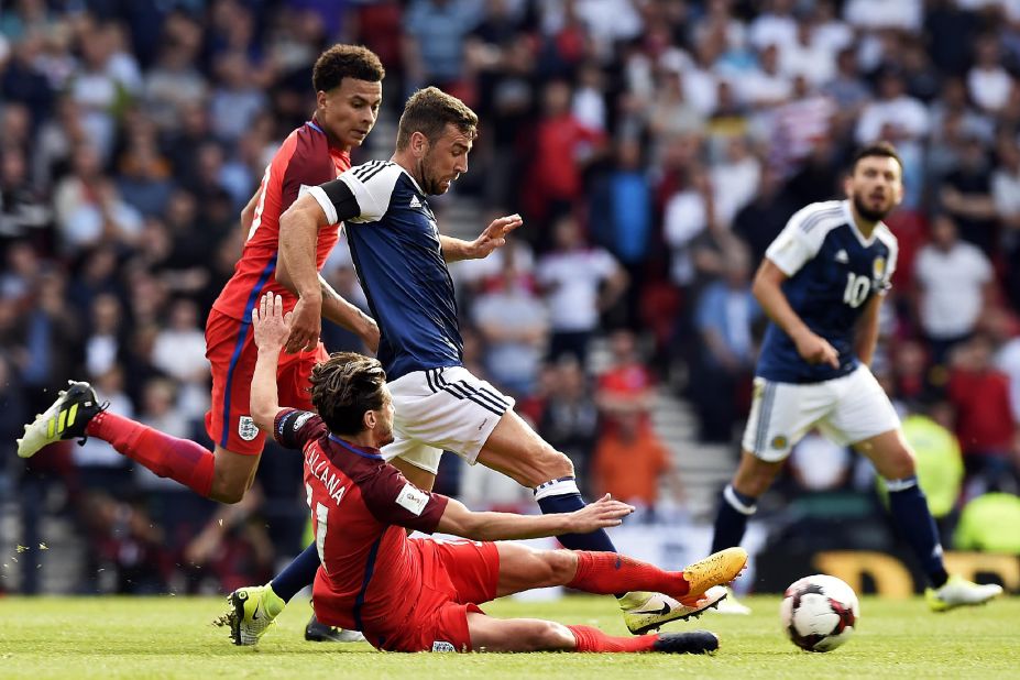 England's midfielder Adam Lallana slides in to tackle Scotland's midfielder James McArthur during the game that ended 2-2. 
