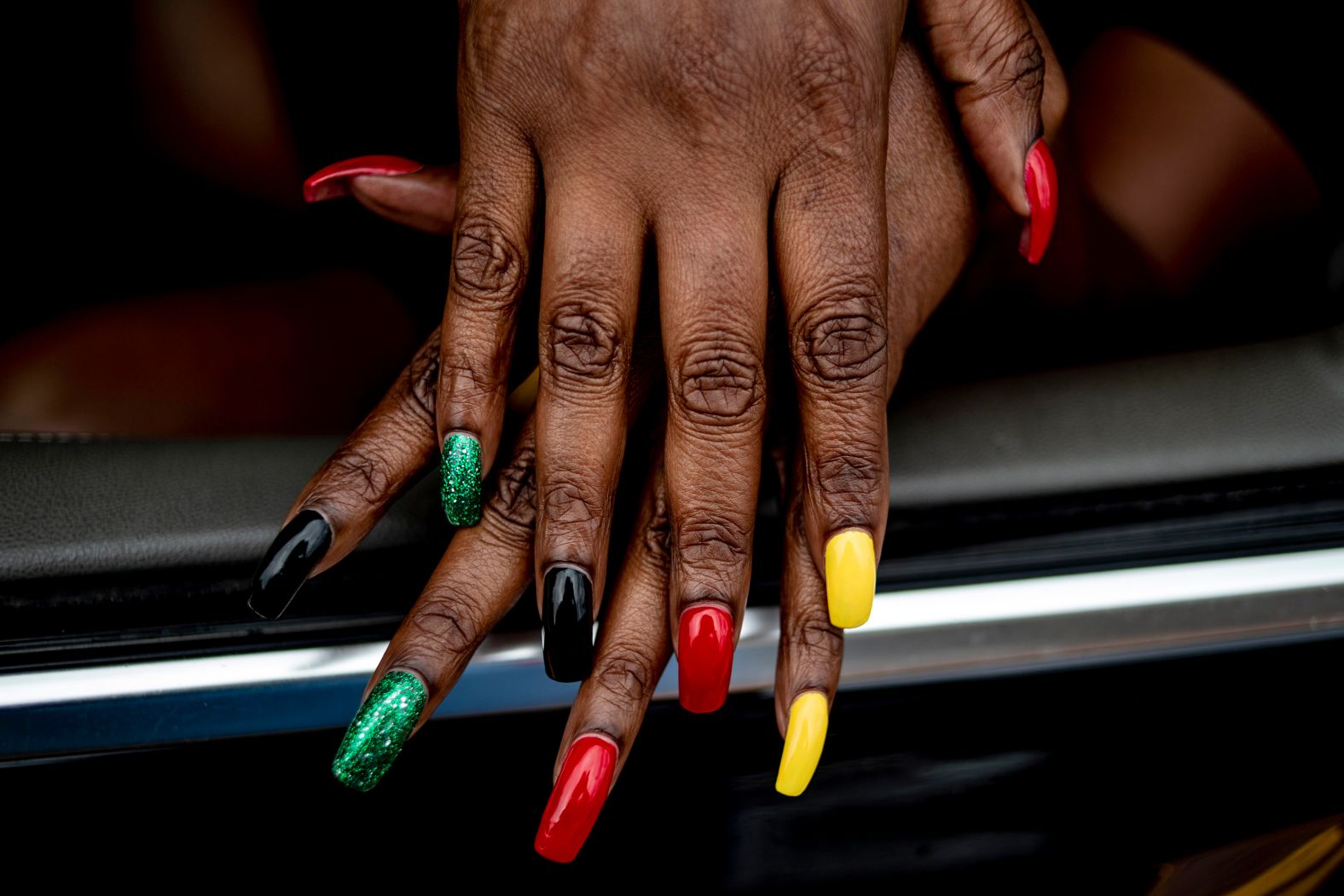 Tracy Palmer shows off her Juneteenth-inspired nails during one of two parades celebrating the holiday in downtown Flint.