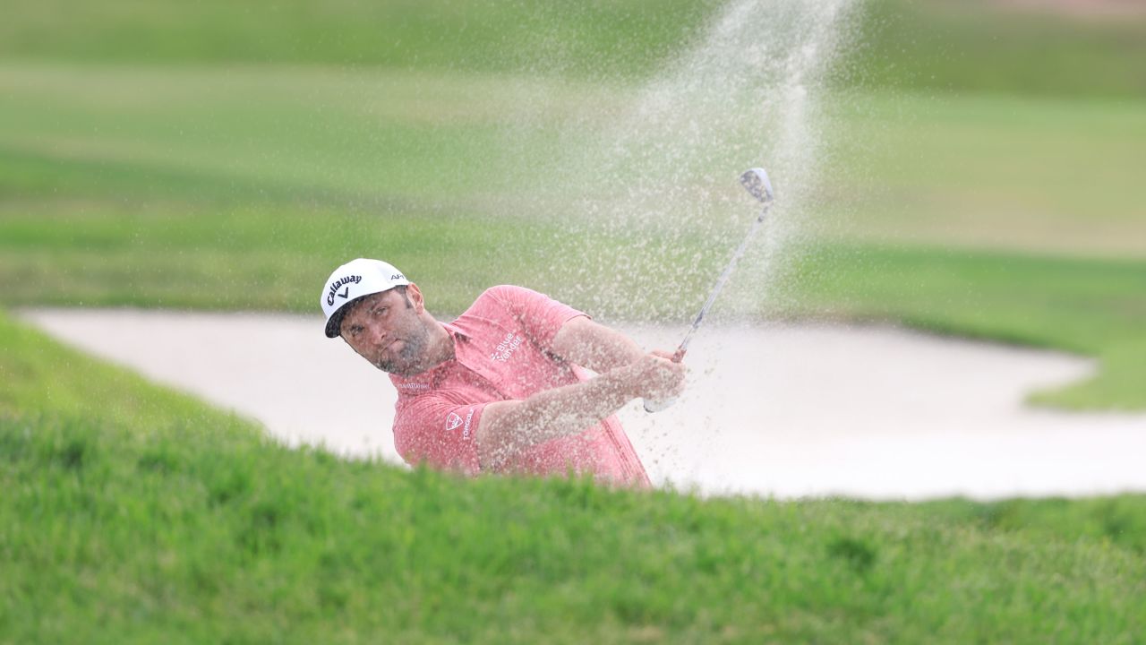 Rahm plays a shot from a fairway bunker on the 17th hole.