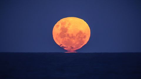 The strawberry moon rises over the ocean on Narrawallee Beach in New South Wales, Australia, on June 6, 2020.