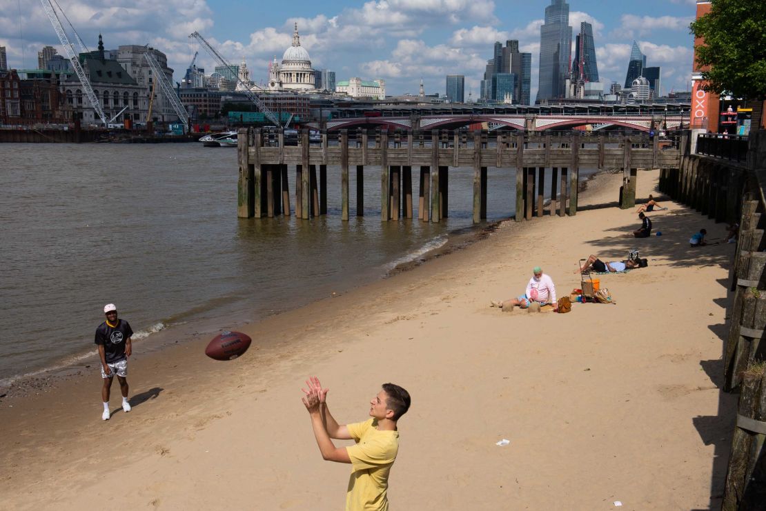 People enjoying the sunshine on the south bank of the River Thames in London last month. A cap on outdoor gatherings is due to lift later this month.