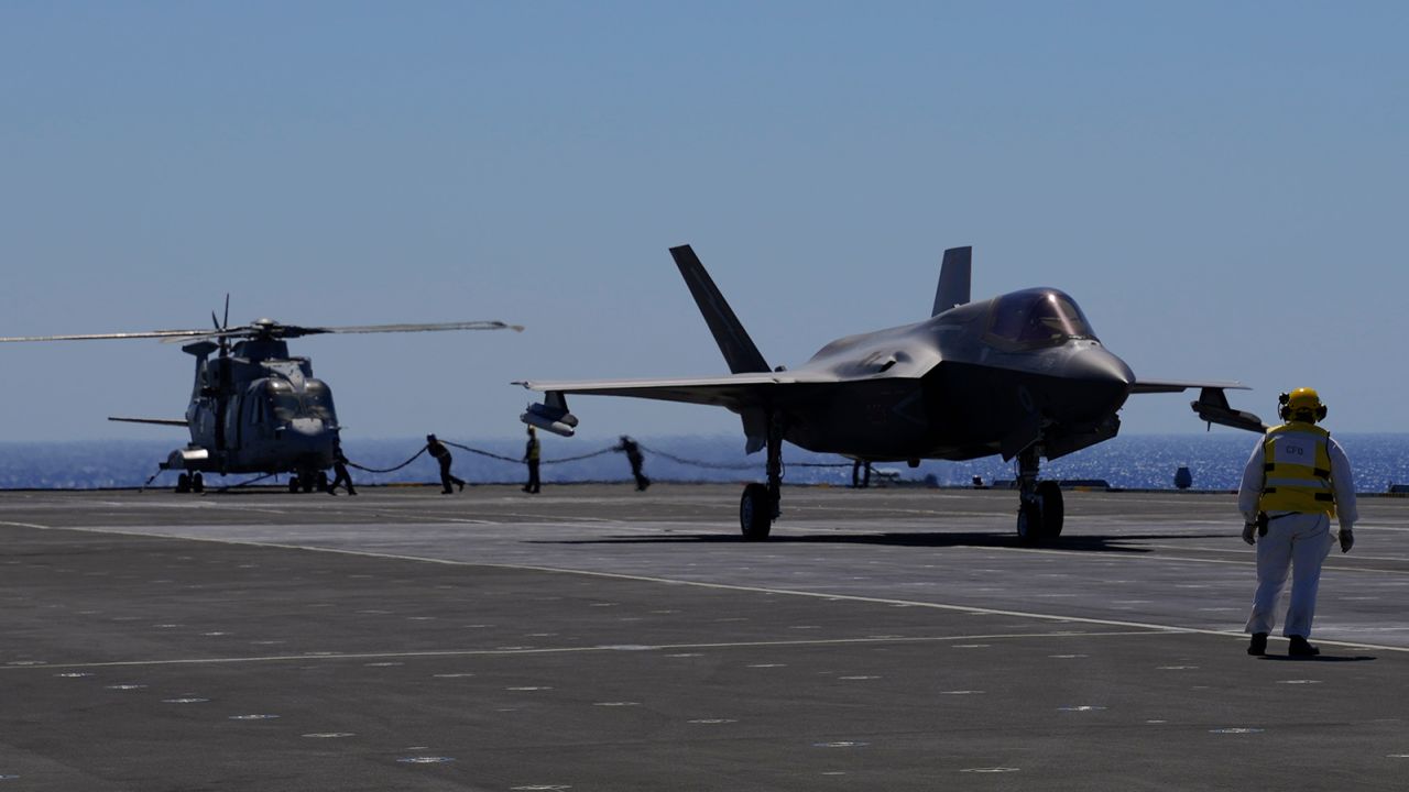 Crew members prepare an F-35B jet (right) for takeoff on the HMS Queen Elizabeth in the Mediterranean Sea on June 20, 2021.