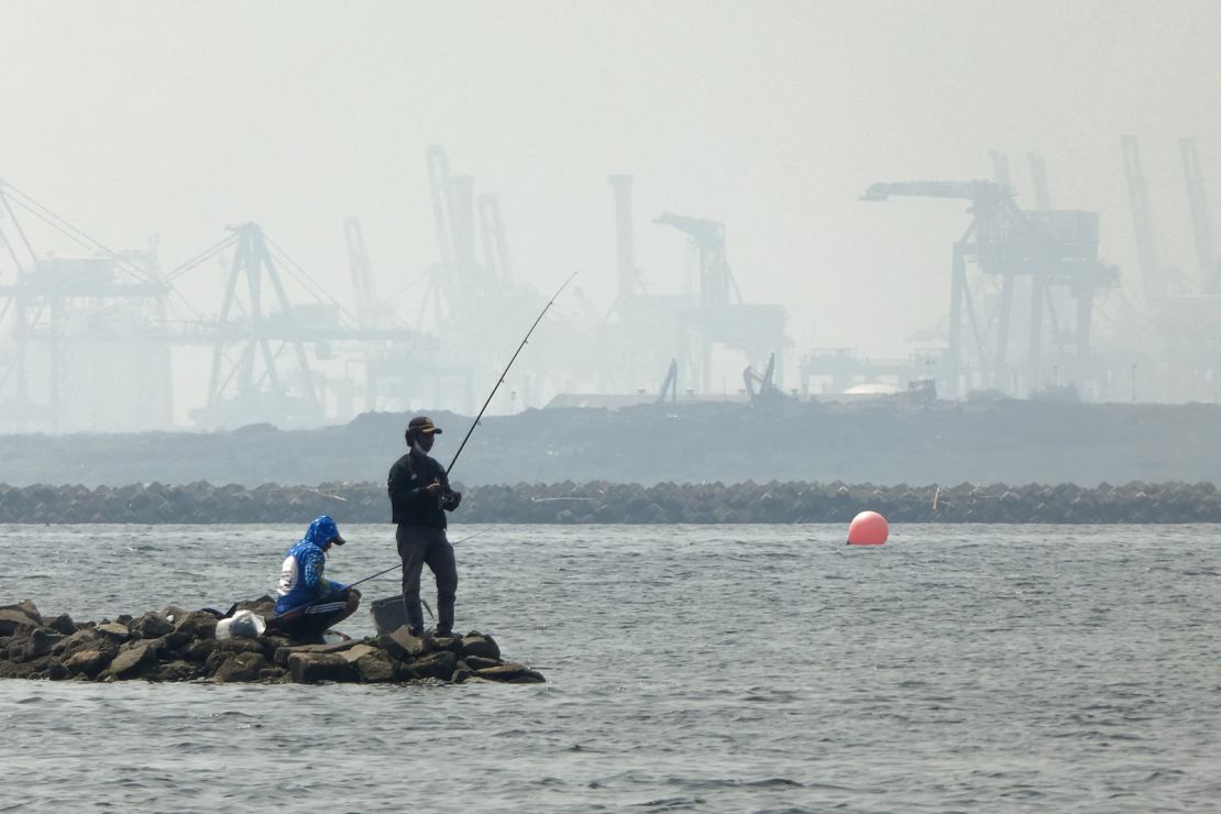Anglers fish amid thick haze at a coastal area in Jakarta on June 20, 2020. 
