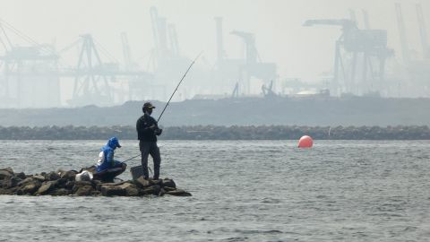 Anglers fish amid thick haze at a coastal area in Jakarta on June 20, 2020. 