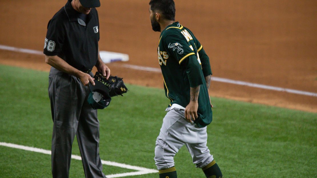 Oakland Athletics pitcher Sergio Romo gives umpire Dan Iassogna his hat and glove and pulls down his pants during a game Tuesday at Globe Life Field in Arlington, Texas.