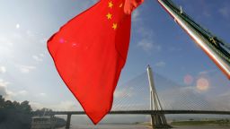China's national flag flies from the back of a ship sailing down the Mekong River (or Lancang River within China) downstream past the Xishuangbanna Great Bridge in Jinghong, 06 July 2005, in Xishuangbanna Dai Autonomous Prefecture which borders Myanmar and Laos in China's southwest Yunnan province. Environmentalists have warned that China's aggressive dam building and development plans threaten fish stocks and add to the pollution of Southeast Asia's strategically important Mekong River, which connects Cambodia, China, Laos, Myanmar, Thailand and Vietnam. AFP PHOTO/Frederic J. BROWN (Photo by Frederic J. BROWN / AFP) (Photo by FREDERIC J. BROWN/AFP via Getty Images)