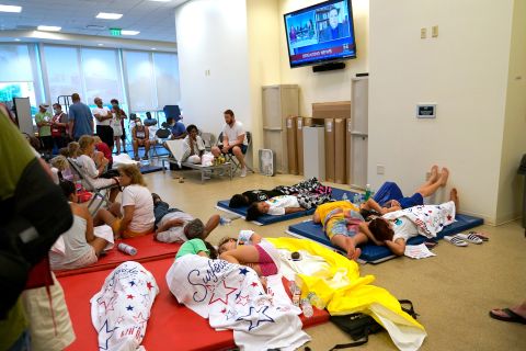 People lie on cots at the family reunification center in Surfside.