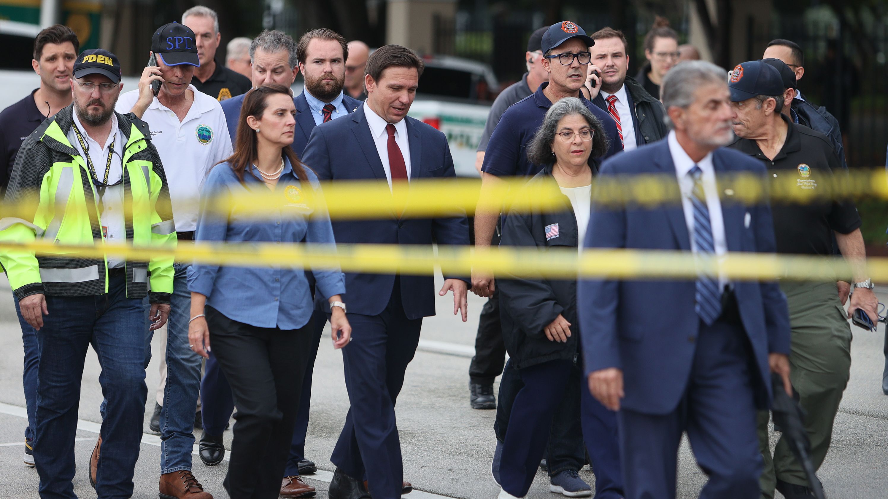 Florida Gov. Ron DeSantis, at center in the red tie, arrives to speak to the media on June 24. "We still have hope to be able to identify additional survivors," DeSantis told reporters near the scene. "The state of Florida, we're offering any assistance that we can."