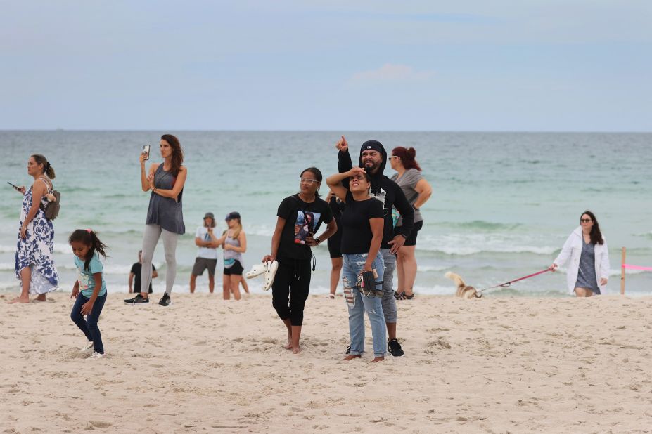 People on the beach look at the building after the partial collapse.