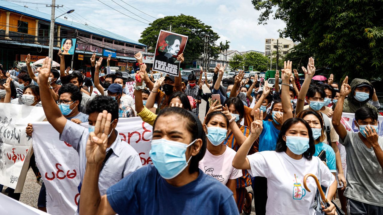 Protesters make the three-finger salute and hold posters of Myanmar's detained civilian leader Aung San Suu Kyi to mark her birthday as they take part in a demonstration against the military coup in Yangon on June 19, 2021.