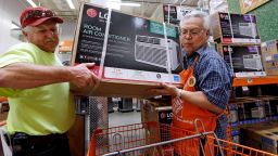 FILE - In this Aug. 1, 2017, file photo, store greeter Danny Olivar, right, lends a hand to a customer to heft an air conditioning unit from a rapidly declining stock at a Home Depot store ahead of an expected heat wave in Seattle. The Home Depot Inc. reports earnings Tuesday, Aug. 14, 2018. (AP Photo/Elaine Thompson, File)