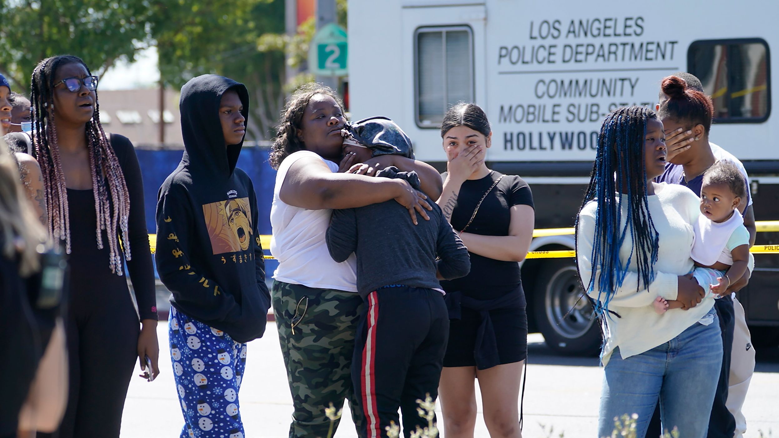 People react Friday at a crime scene in the Hollywood Hills neighborhood in Los Angeles.