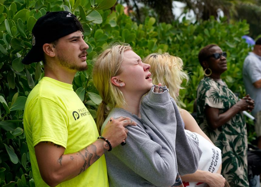 Ariana Hevia, center, stands with Sean Wilt near the partially collapsed building on June 25. Hevia's mother, Cassandra Statton, lives in the building.