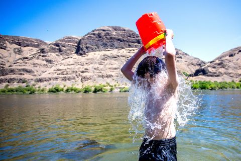 John Elizondo, 11, dumps a bucket of water over himself while playing in the Snake River at the edge of Asotin, Washington, on June 24.