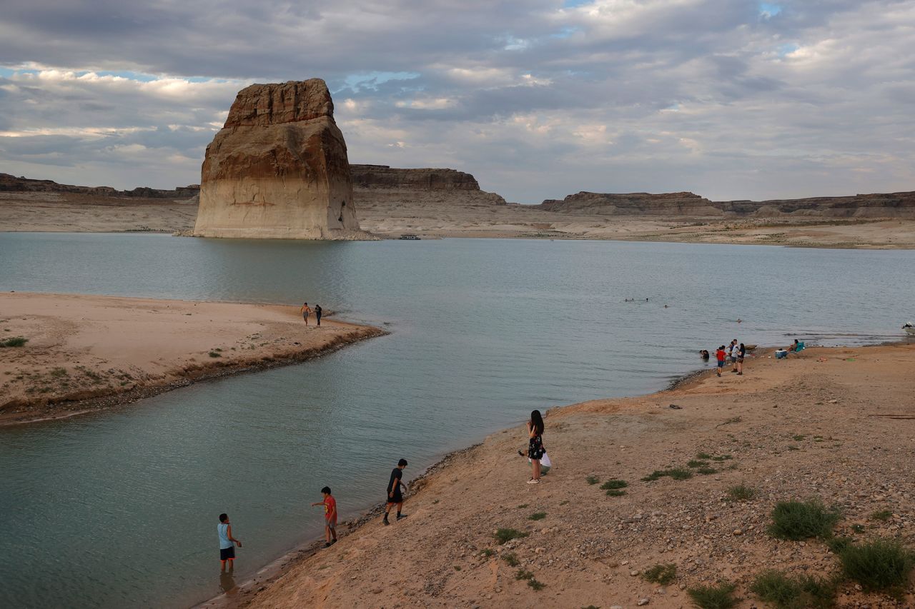 Park visitors in Big Water, Utah, walk on an area of Lake Powell that used to be underwater at Lone Rock Beach in June 2021.