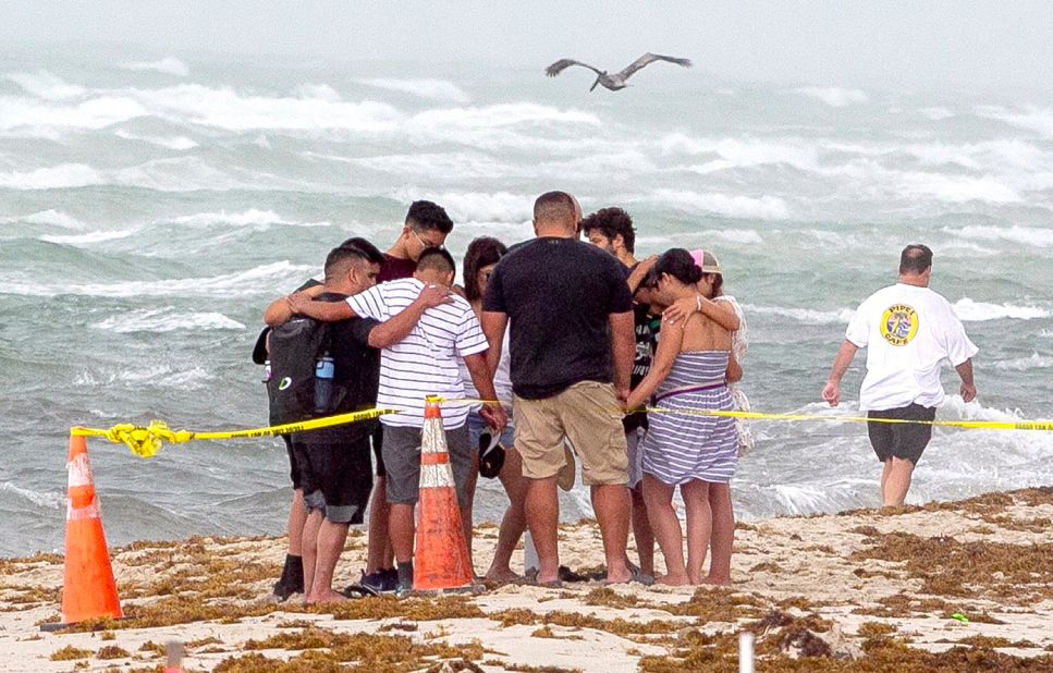 People pray together on the beach near the collapsed building.