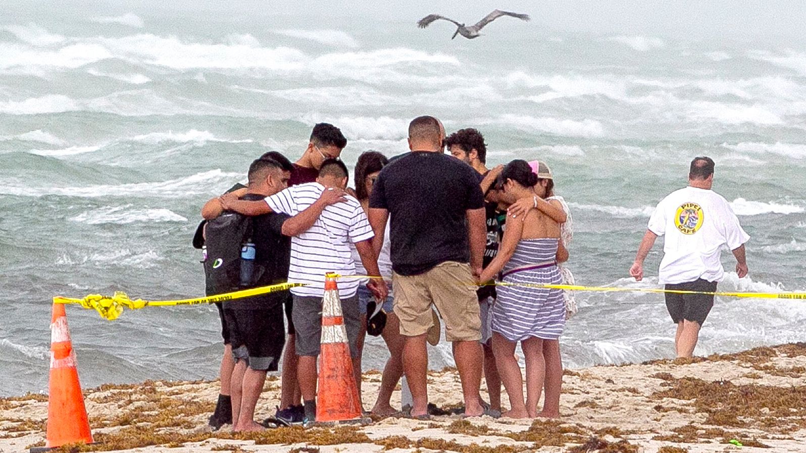 People pray together on the beach near the collapsed building.