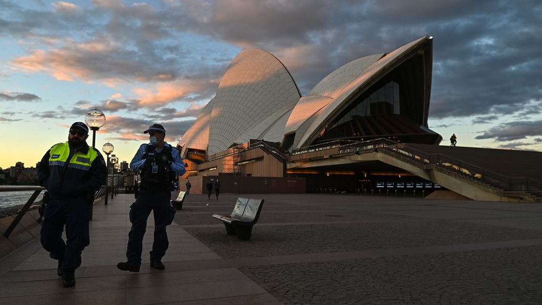 Police officers walk past the Sydney Opera House during the first day of lockdown on Saturday.