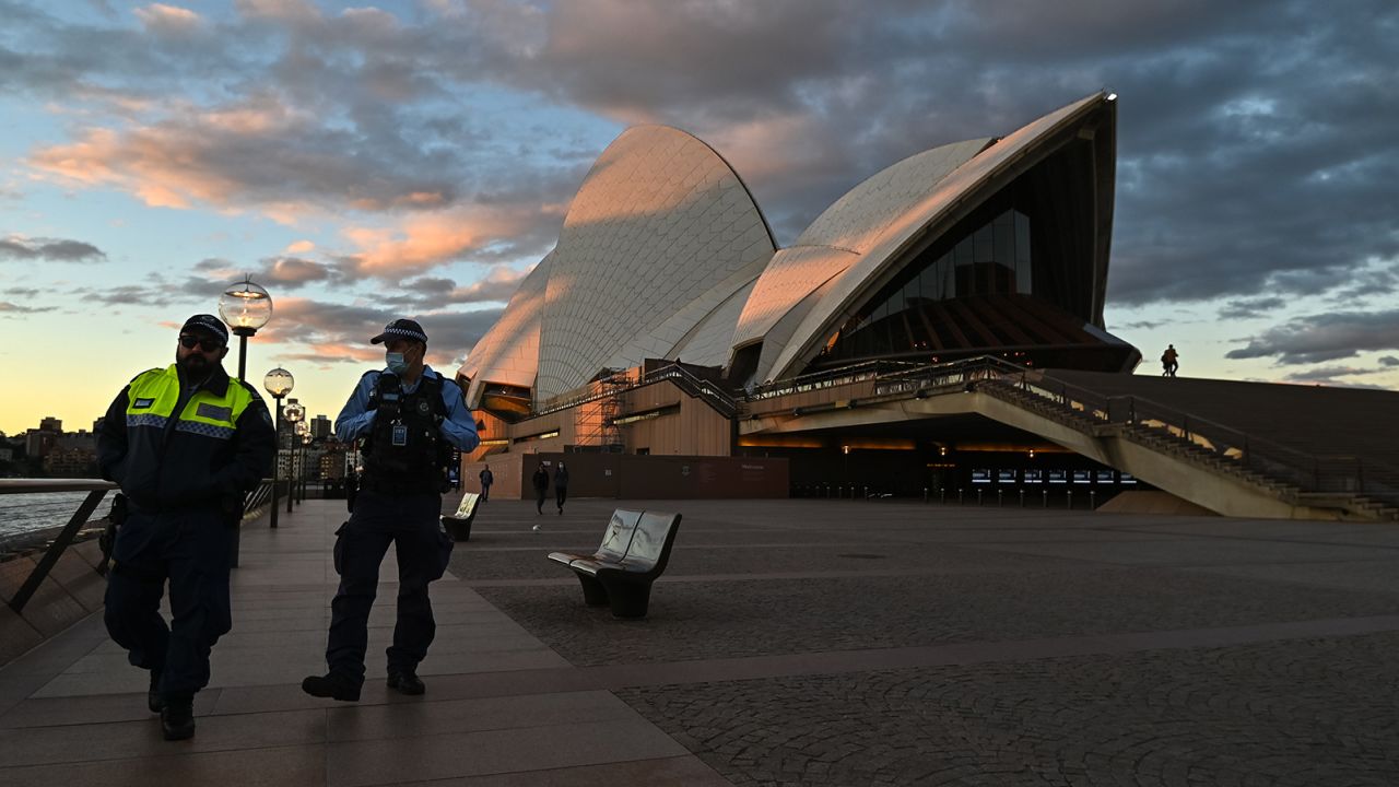 Police officers walk past the Sydney Opera House during the first day of lockdown on Saturday.