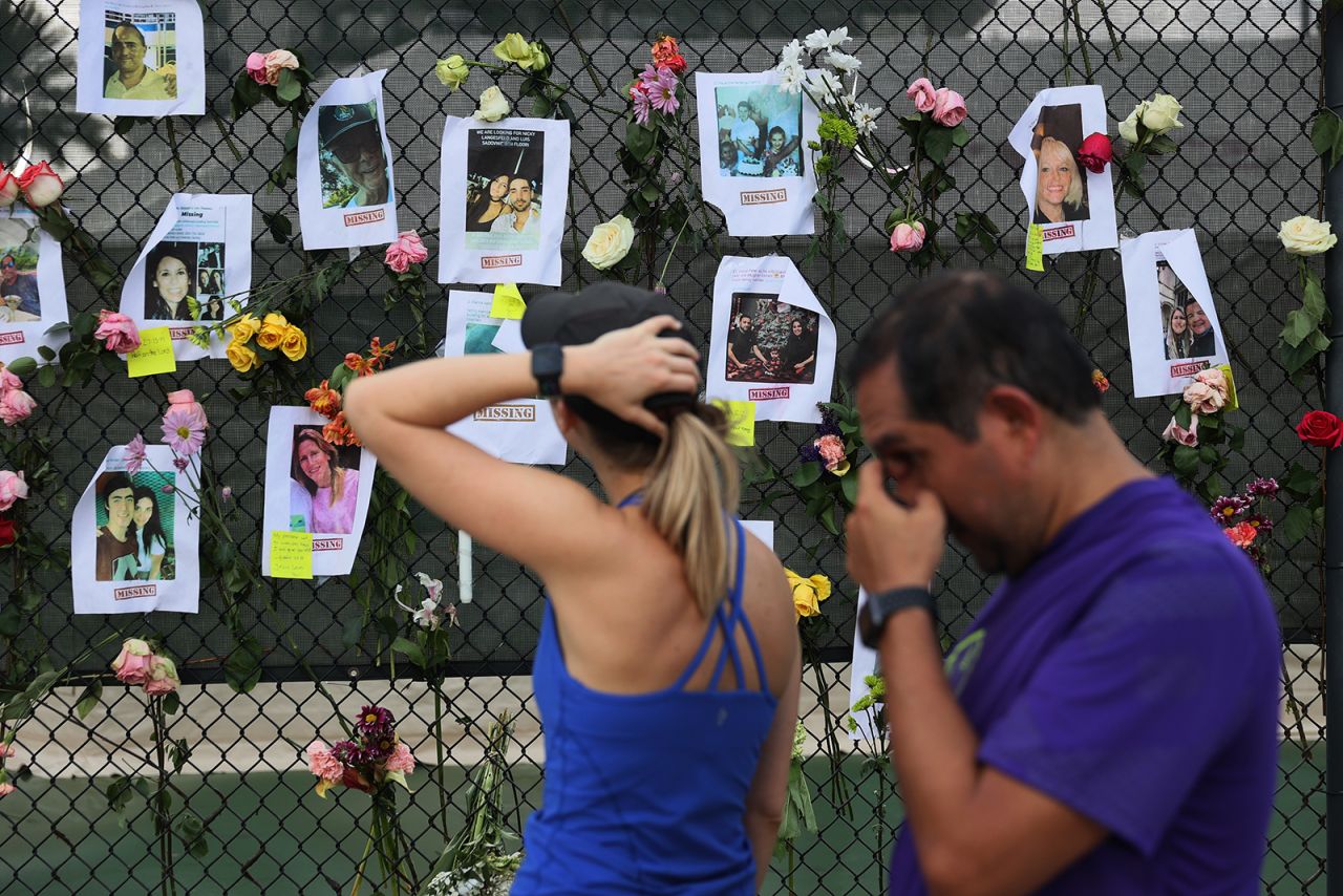 Passersby look at photos of missing people.