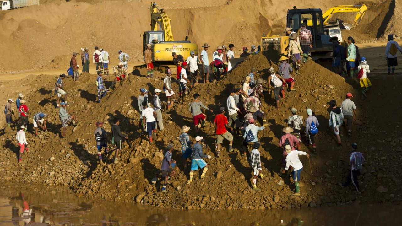 Freelance miners digging for raw jade stones in piles of waste rubble dumped by mechanical diggers, next to a jade mine in Hpakant on October 4, 2015.